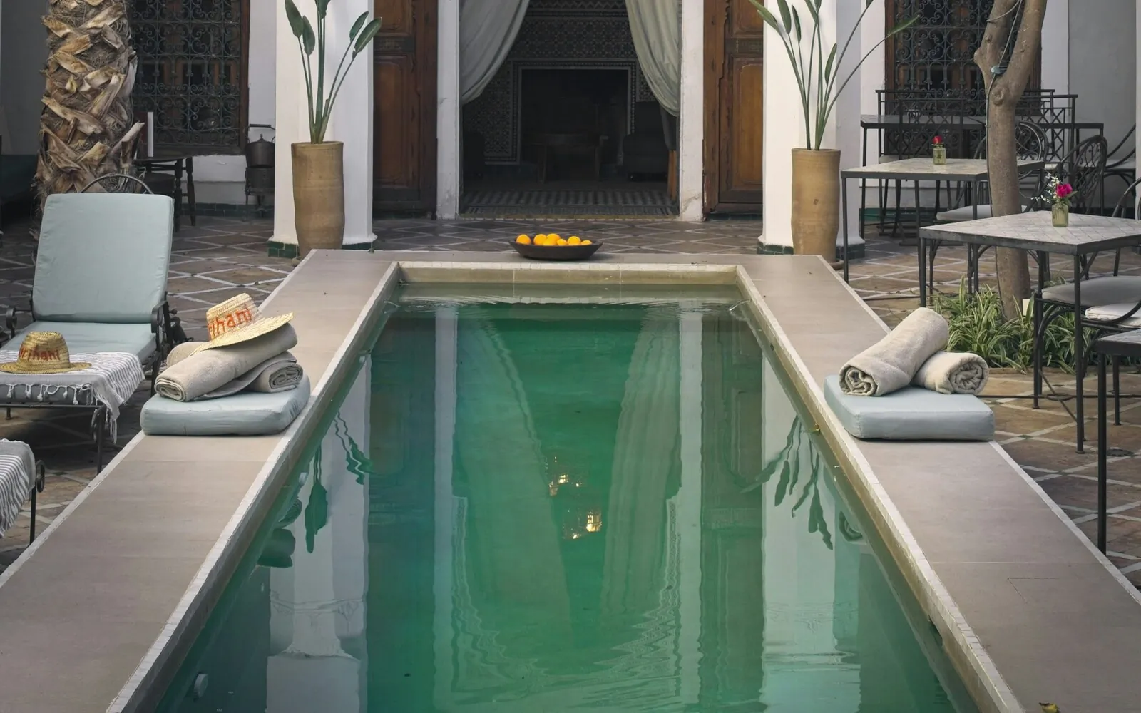 Boutique hospitality courtyard with a narrow pool, planted edges, and arched colonnades